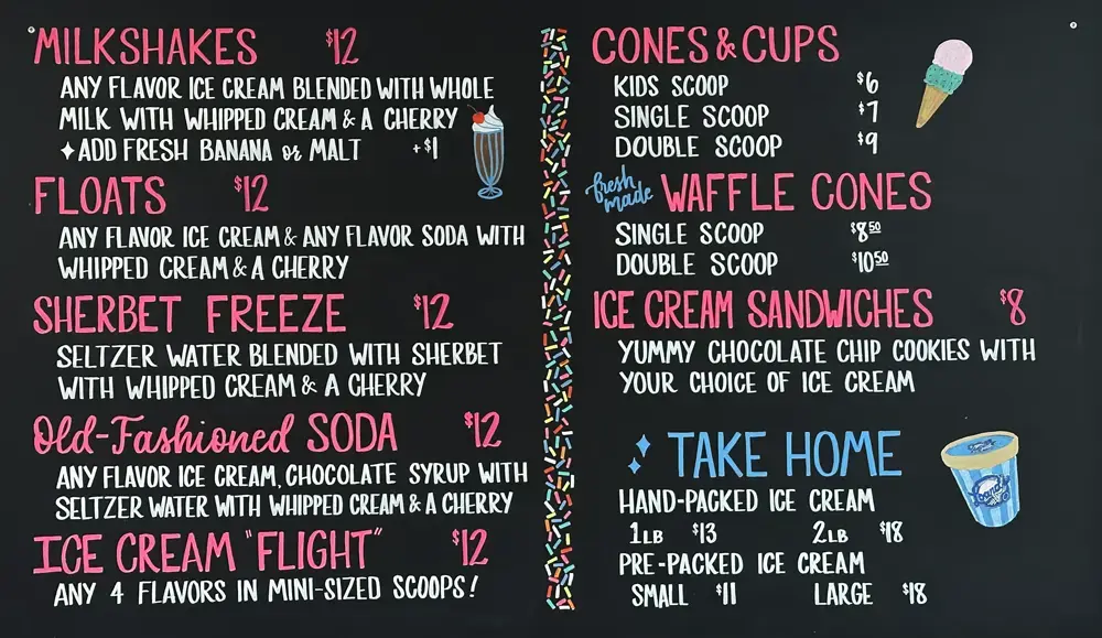 Black chalkboard with menu for specialties like milkshakes, floats, soda, cones, and ice cream sandwiches