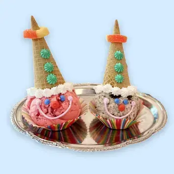 A scoop of ice cream and a upside-down cone decorated like a clown